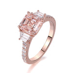 Rose gold ring with a large pink gemstone and smaller clear stones on a white background