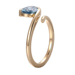 Pear cut blue lab grown diamond ring showing sculptural gold bypass band