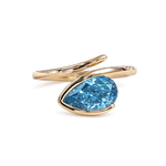 Pear cut blue lab diamond ring in yellow gold with sculptural bypass setting