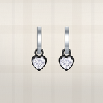 Heart-shaped diamond earrings on a light beige background
